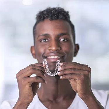 Patient holding clear aligners offered at Superior Orthodontics in Metro Detroit, MI