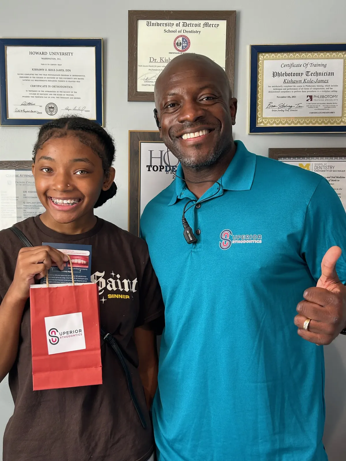 Dr. Kishawn Kole-James with a smiling patient in front of his orthodontic credentials at Superior Orthodontics in Metro Detroit, MI