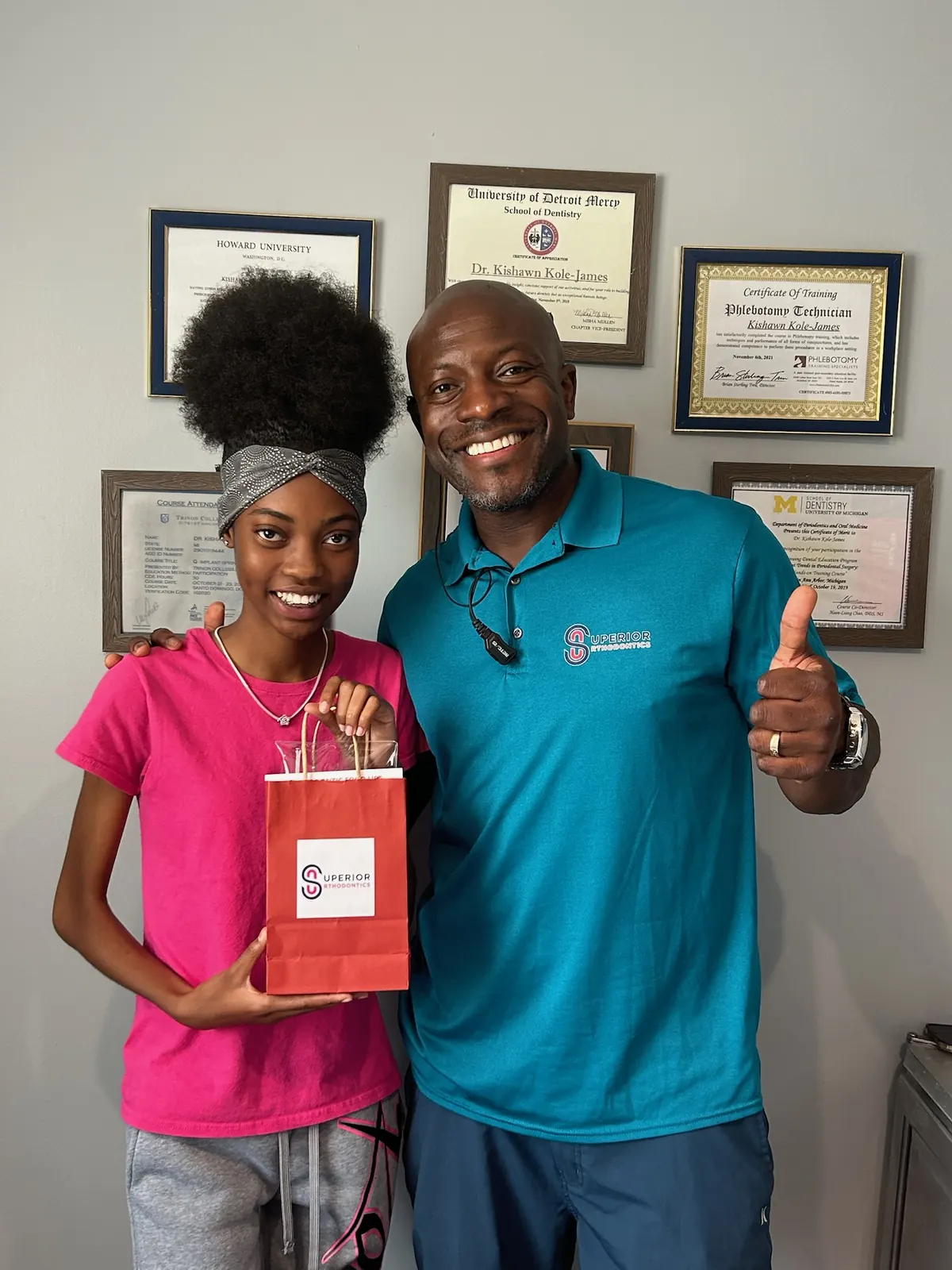 Dr. Kishawn Kole-James with a smiling patient in front of his orthodontic credentials at Superior Orthodontics in Metro Detroit, MI