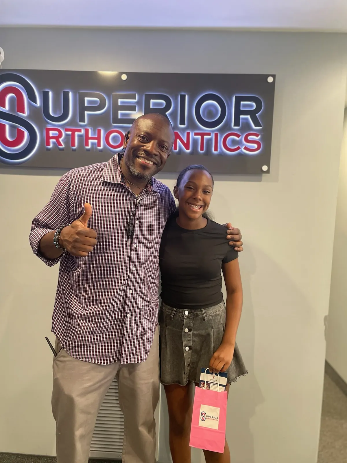 Dr. Kishawn Kole-James giving a thumbs up with a young patient under the Superior Orthodontics sign in Metro Detroit, MI
